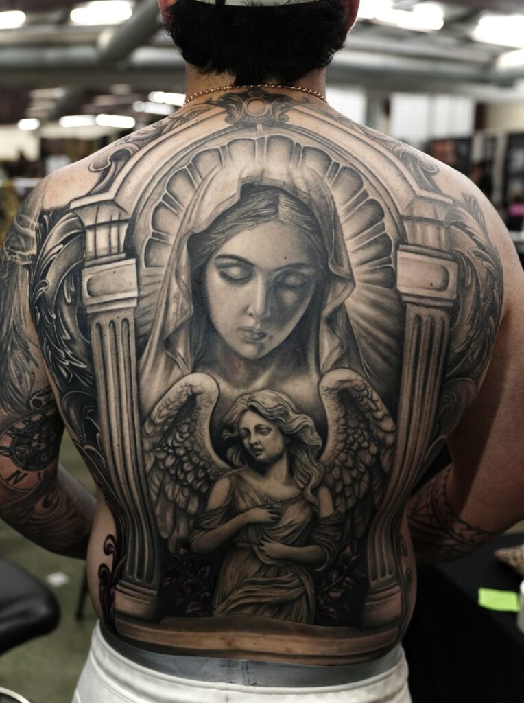 Full-back black-and-grey realism piece — Virgin Mary with angel, by Arly Rojano